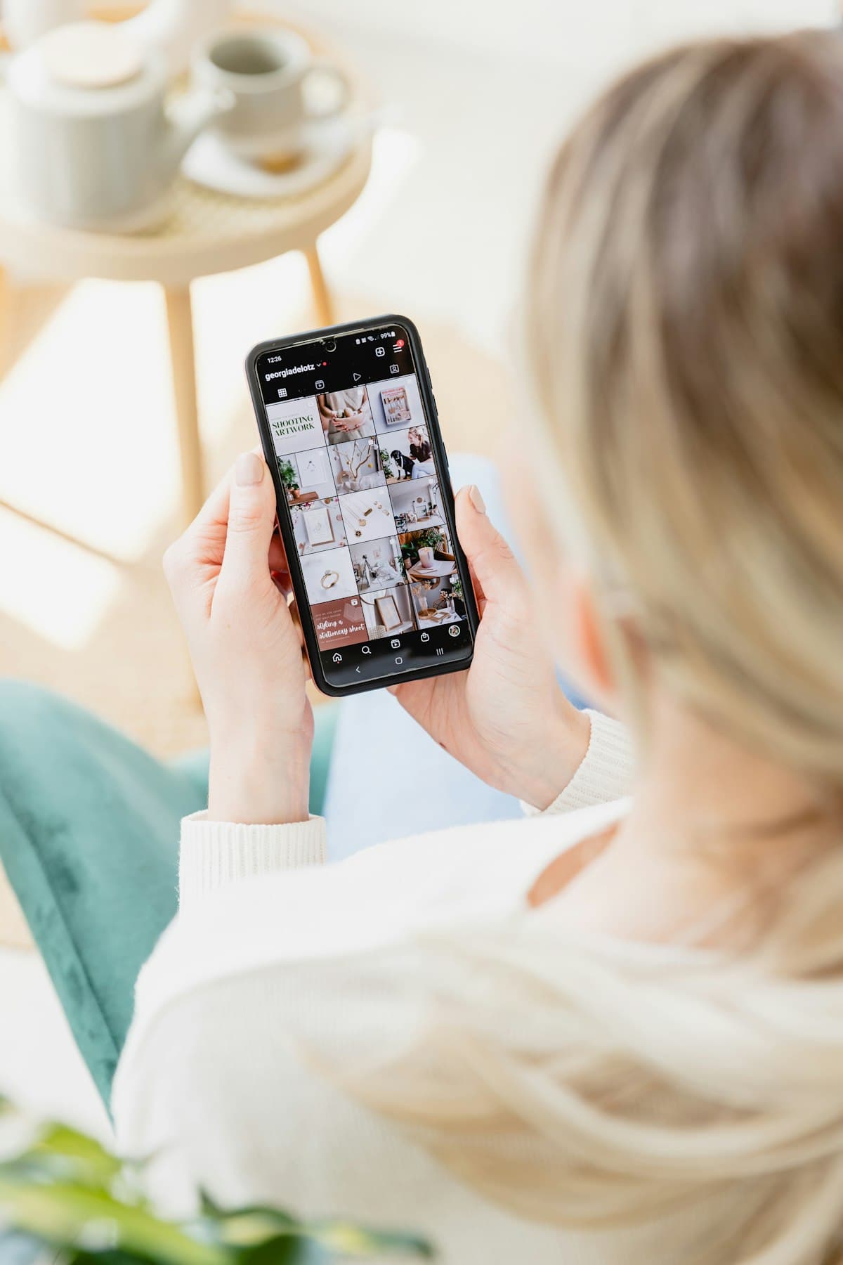 Mão segurando um celular com um perfil do Instagram aberto na tela