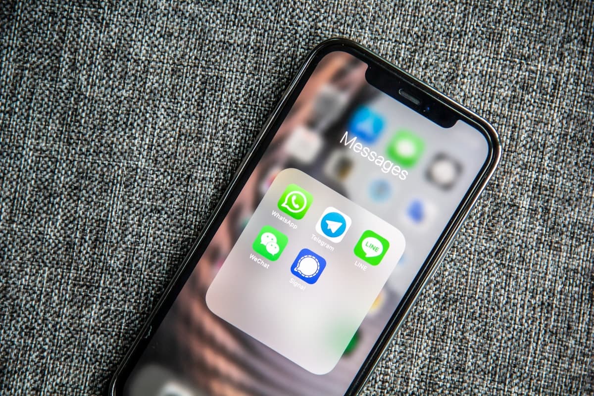 Celular sobre um sofá com o ícone do WhatsApp em destaque na tela